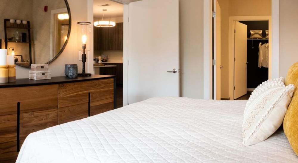 Bedroom with dresser and round mirror at The Current on River in Hackensack, New Jersey
