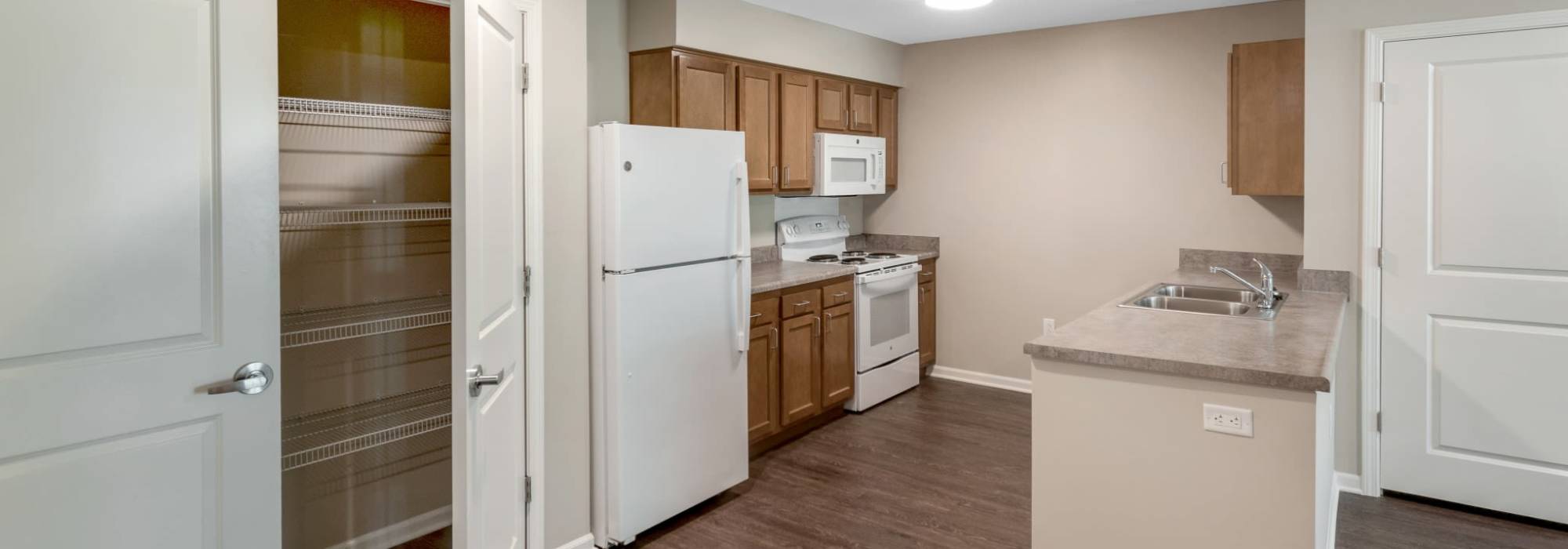 Kitchen with pantry and white appliances at Magnolia Greene in Lavale, Maryland