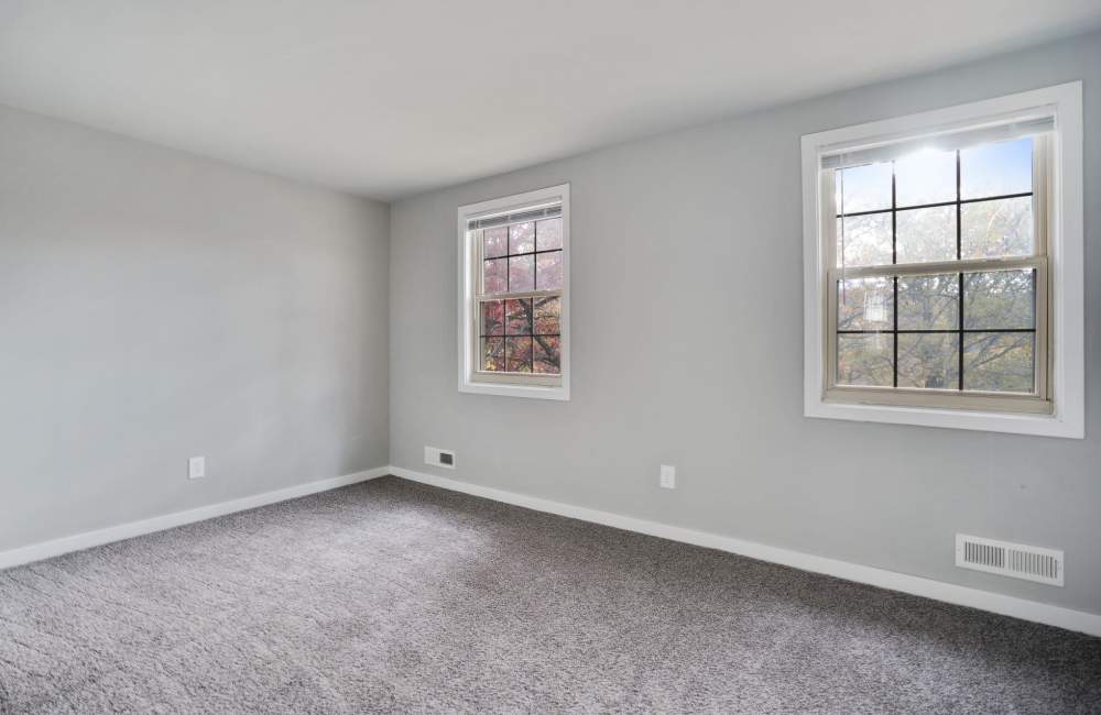 Spacious room with two windows and soft carpet flooring, natural light streaming in at Fairway Ridge in Baltimore, Maryland