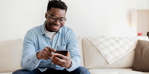 A resident looking at a phone on the couch at Canterbury Heights in Asheville, North Carolina