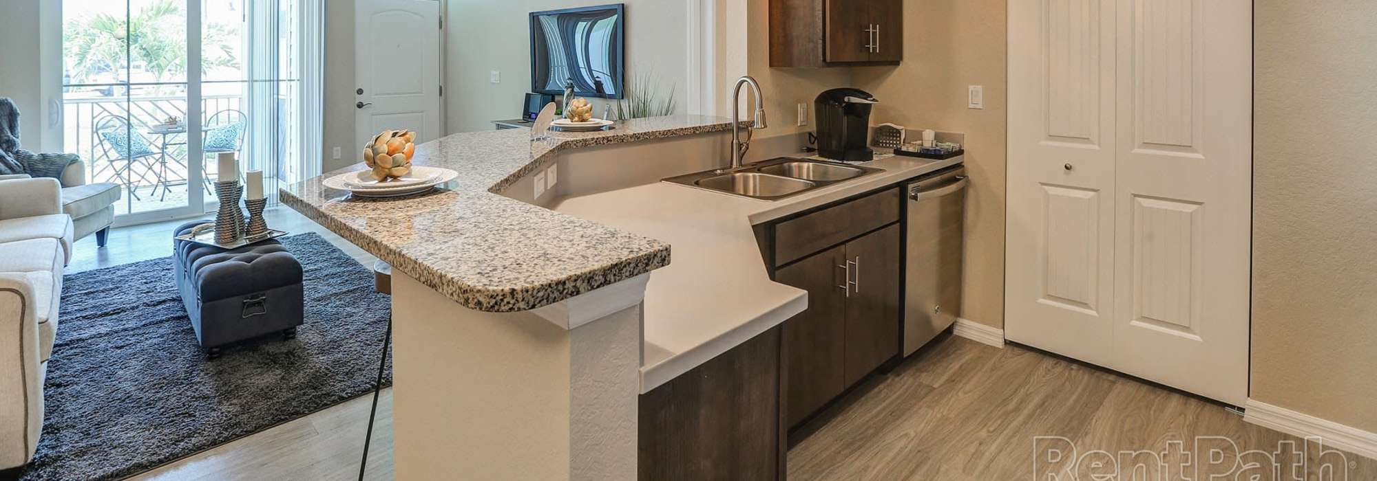 Charming modern kitchen with stylish granite countertops and inviting living area at Lemon Bay Apartments in Englewood, Florida.
