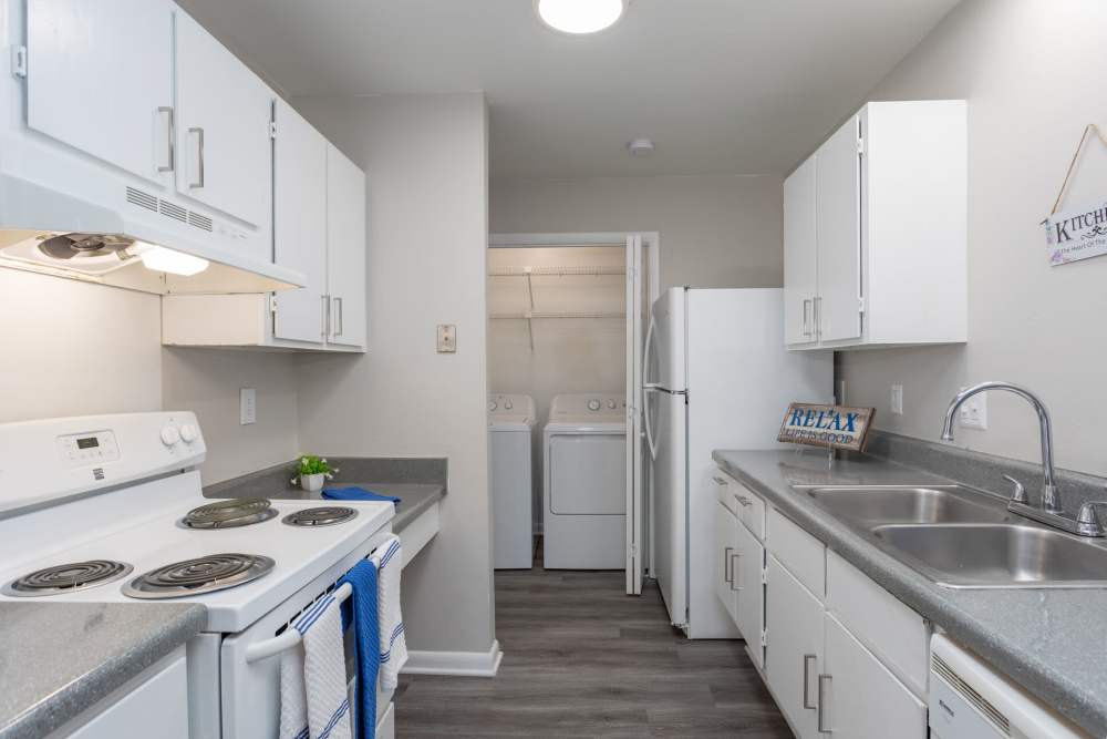Modern kitchen with white appliances and wood-style flooring at Landmark Flats in Fayetteville, North Carolina