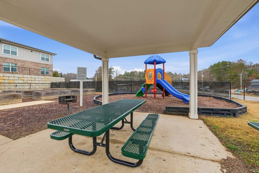 Inviting playground area with shaded picnic tables at Flats At Sam Lane in Ringgold, Georgia.