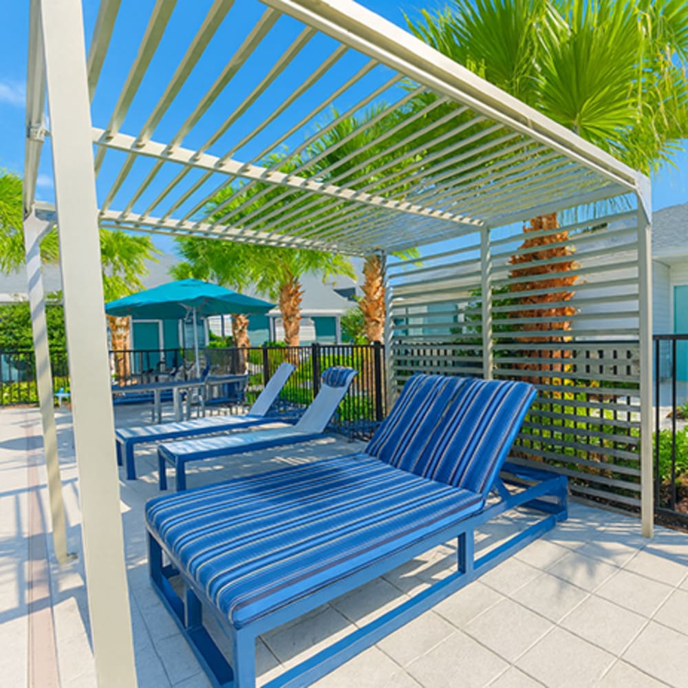 Pool cabana with blue lounge chairs at Viva At Palm Coast in Palm Coast, Florida