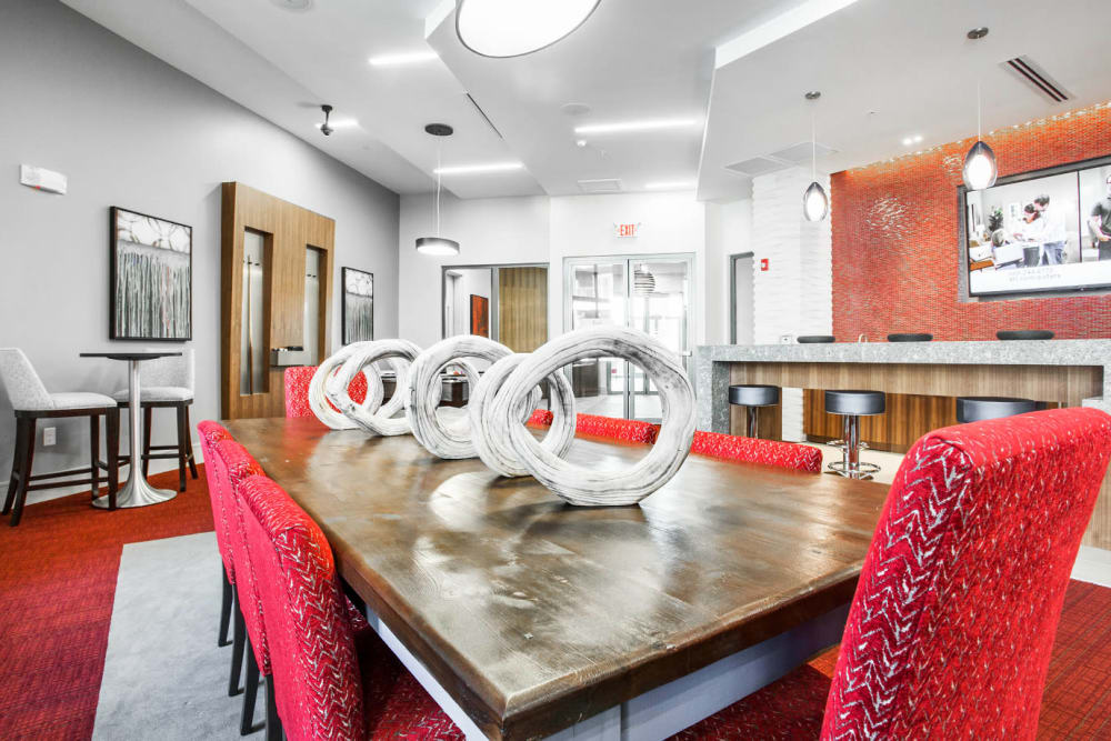 Large dining table for eight with red, cushioned chairs in community room at Marq Midtown 205 in Charlotte, North Carolina
