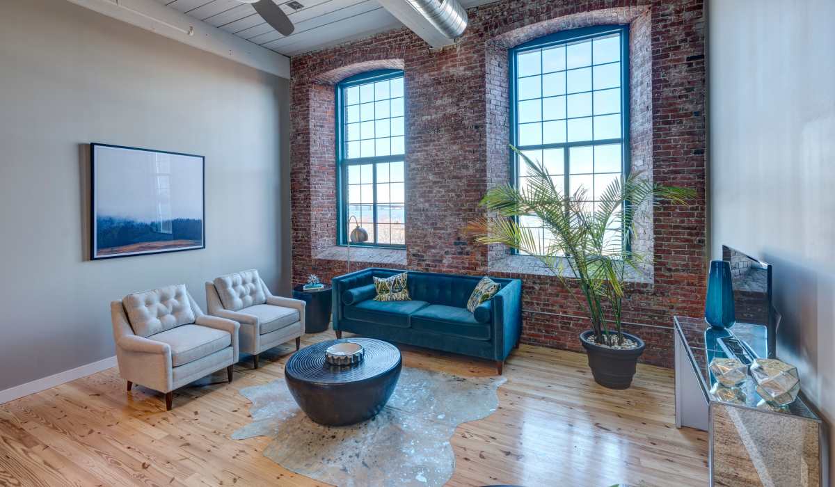 New gray chairs and green couch with large windows at Commonwealth Landing Lofts in Fall River, Massachusetts
