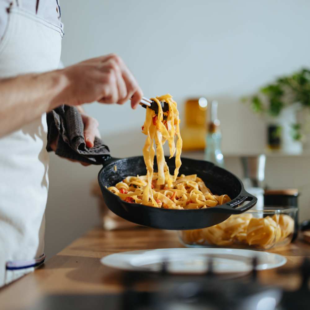 Resident cooking pasta in a black skillet at Atrium Gardens in Arlington, Texas
