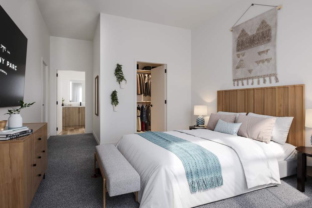 Bedroom with grey carpet and brown wooden bed with white linens