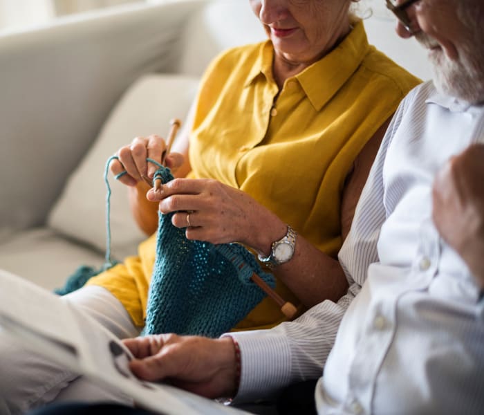 Two residents sitting on a couch, one of them knitting at Randall Residence of Fremont in Fremont, Ohio