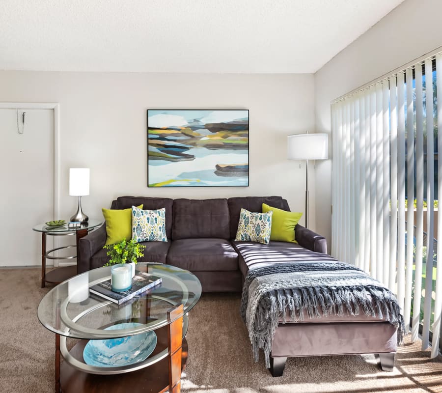 Model living room with cozy furnishings and sliding door access to a private patio at Executive Apartments in Miami Lakes, Florida