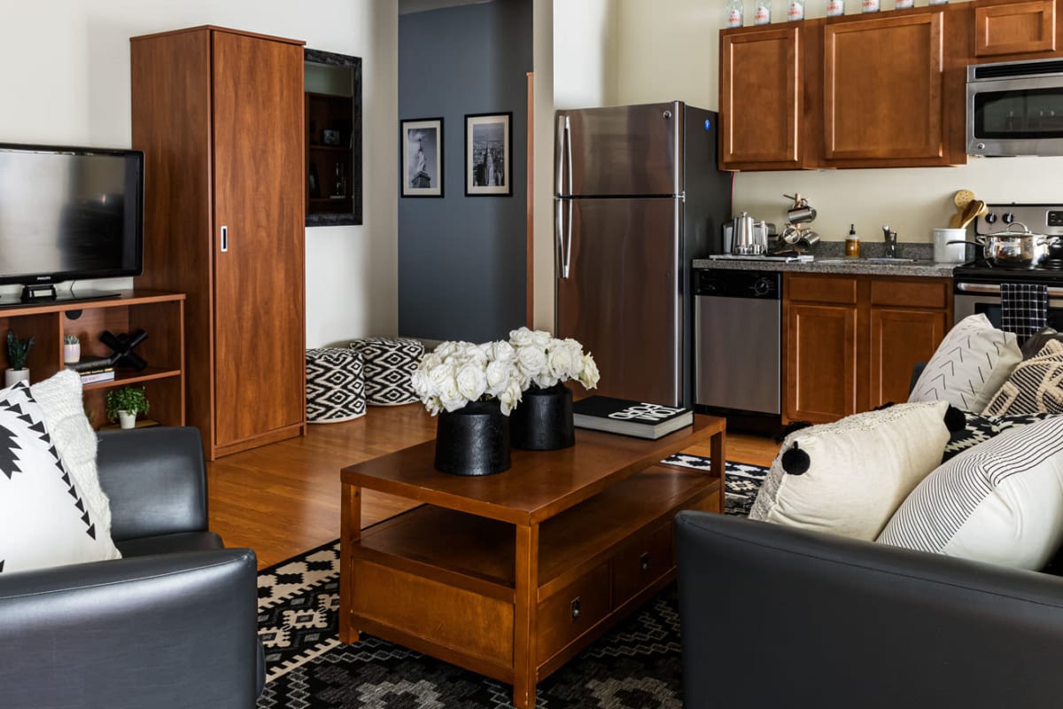 Modern furnishings and custom wood cabinetry in a model student apartment's open-concept living and kitchen areas at 20 Hawley in Binghamton, New York