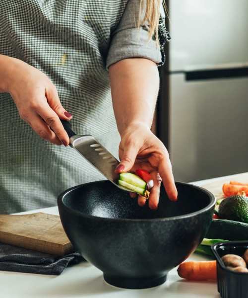 Resident chopping vegetables in her kitchen with granite countertops and stainless-steel appliances at Linden Hill in Magna, Utah