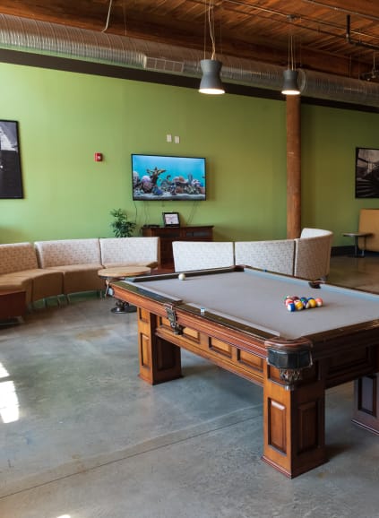 Covered outdoor community space with couch seating and hanging basket chairs at Loray Mill Lofts in Gastonia, North Carolina
