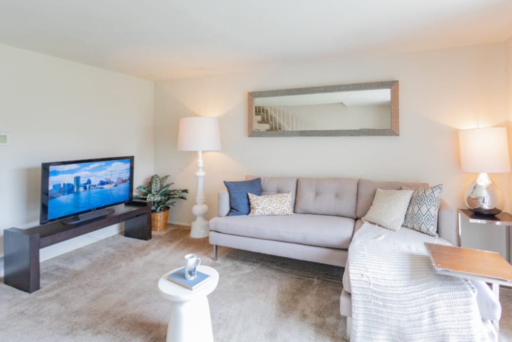 Cozy living room with plush sofa, large TV, decorative pillows, and ambient lighting at Dutch Village Apartments in Baltimore, Maryland