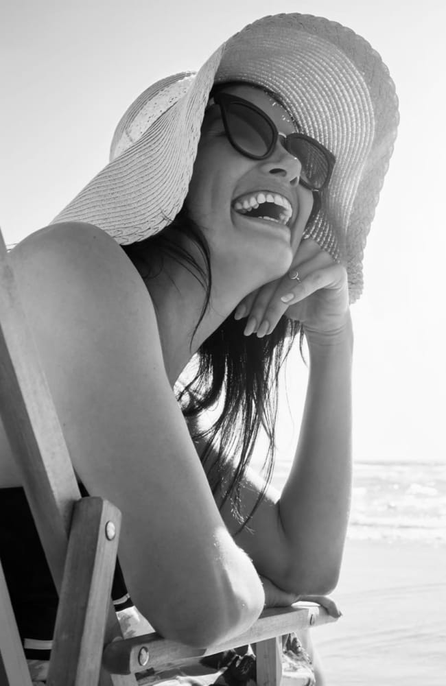 Woman sitting in a chair with a big hat at the beach near Inscription West Palm Beach in West Palm Beach, Florida