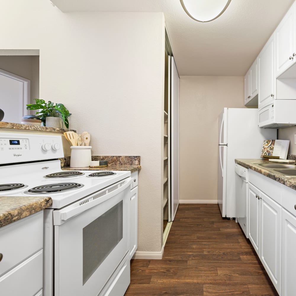 Kitchen with white appliances and cabinets at Allina La Jolla in San Diego, California