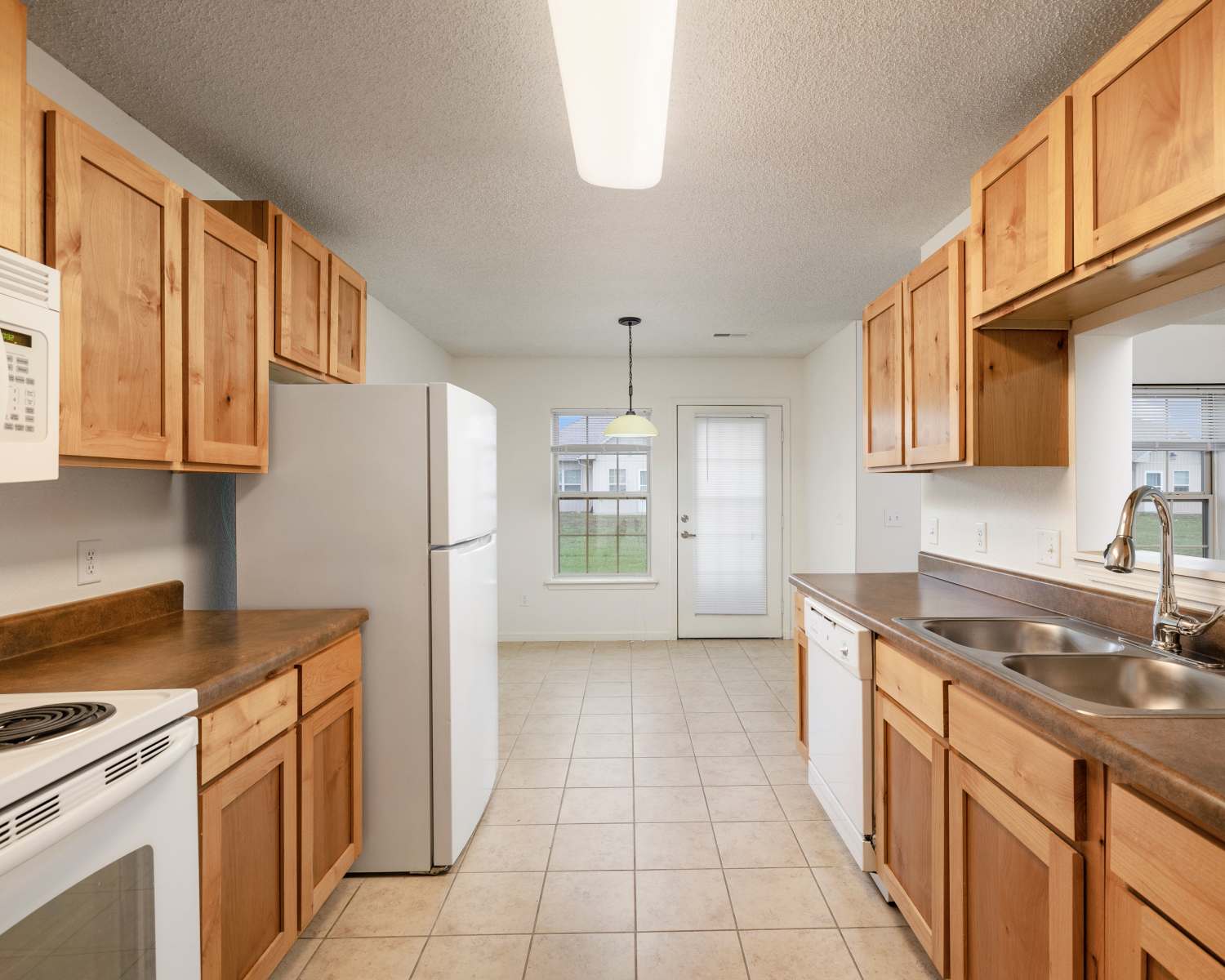 kitchen with wooden cabinets, white appliances, and double sink at Oaklawn Estates in Rogersville, Missouri