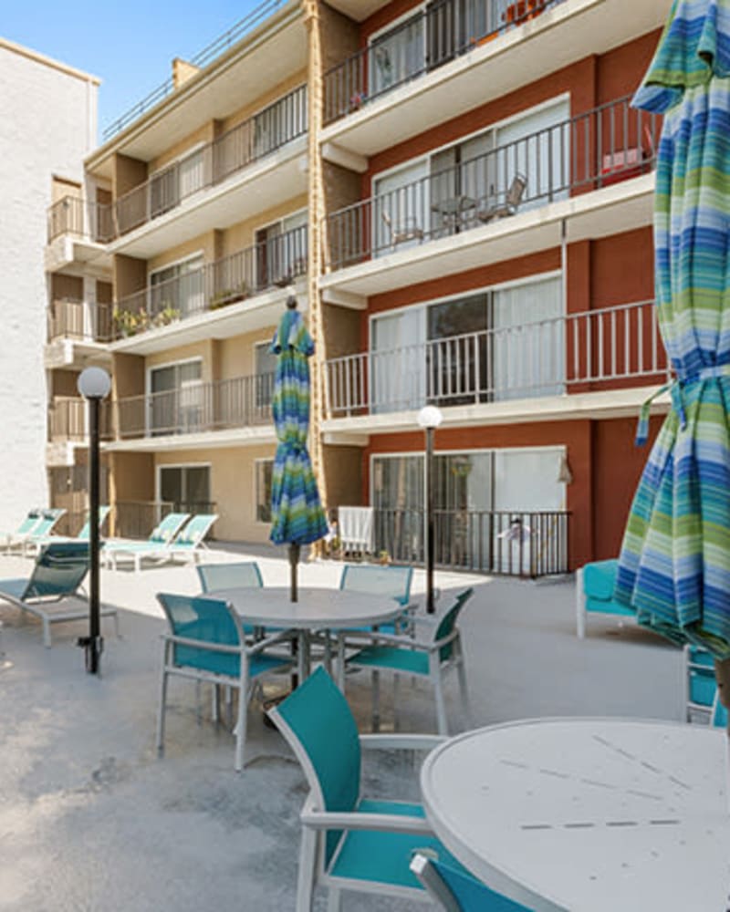 Pool patio with tables and umbrellas at Amanda Regency Apartments, Van Nuys, California