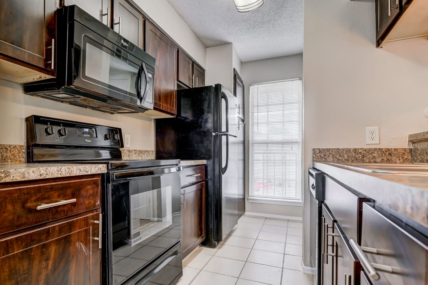 Fully equipped kitchen with sleek black appliances and granite countertops at Grand Seasons Apartment Homes in Dallas, Texas