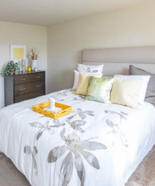 Bright bedroom with floral bedding, wooden dresser, and decorative accessories, inviting and cozy atmosphere at Dutch Village Apartments in Baltimore, Maryland