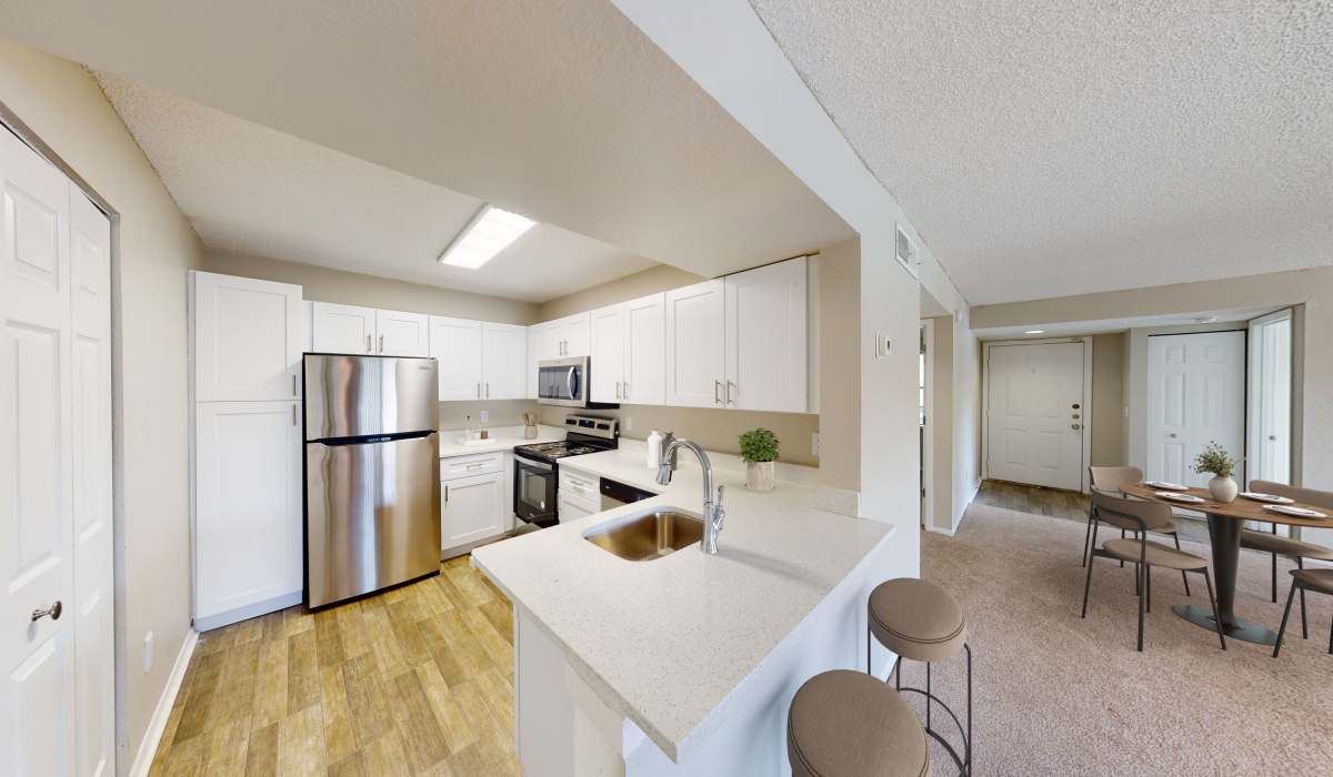 Open-concept kitchen with island, stainless steel appliances, and adjacent living area at Cypress Run in Orlando, Florida