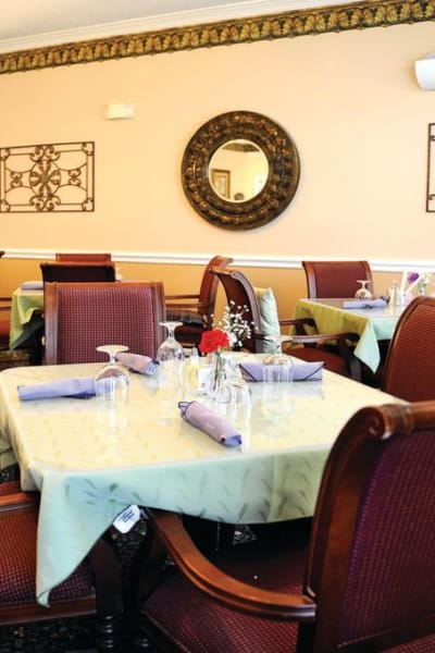 Dining hall with tables set for four at Quail Park of Granbury in Granbury, Texas