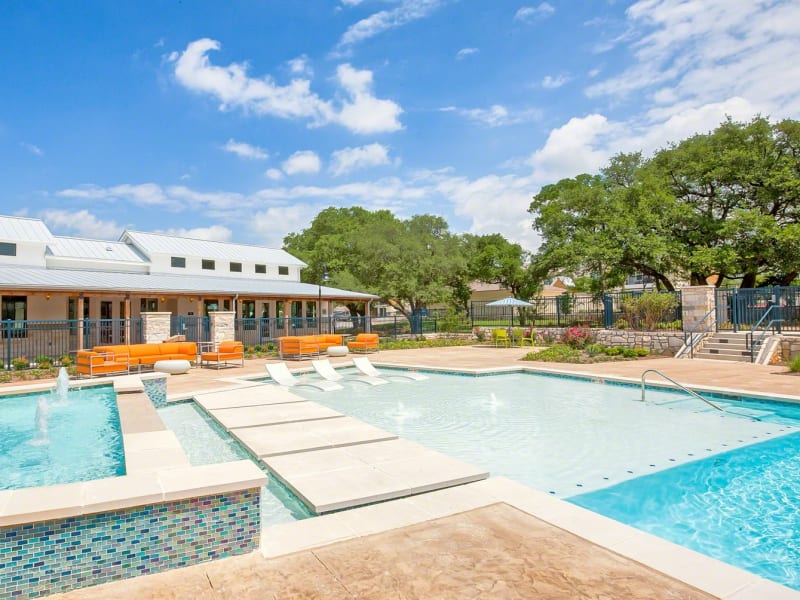 Sparkling resort-style swimming pool with an expansive sundeck and poolside lounge seating at Creekside at Kenney's Fort in Round Rock, Texas