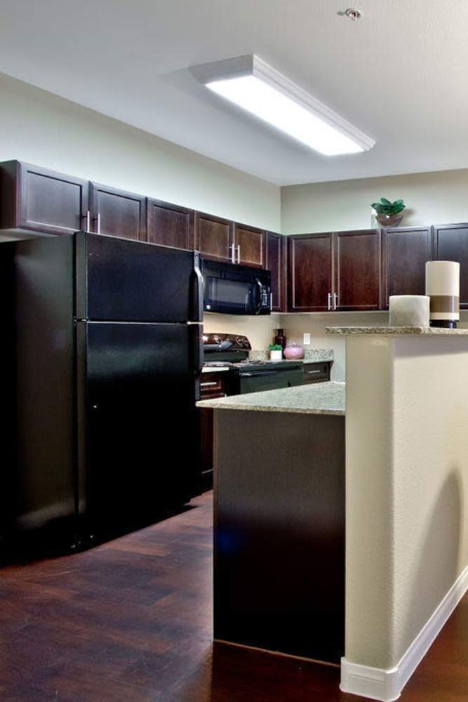 Kitchen with black appliances and wooden cabinets at Acapella in Las Vegas, Nevada