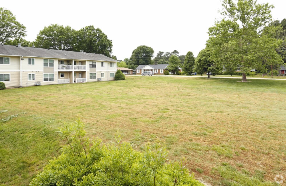 A grass field next to an apartment at Honeytree Apartments in Raleigh, North Carolina