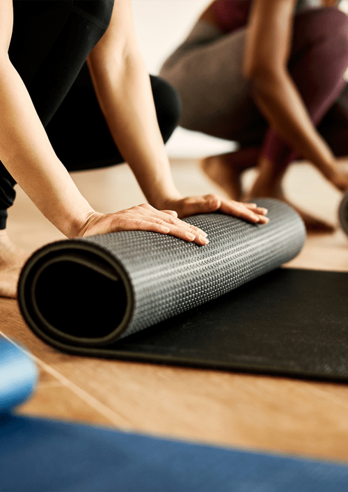 Resident rolling up a yoga mat at The Gardens on Stadium in Phenix City, Alabama