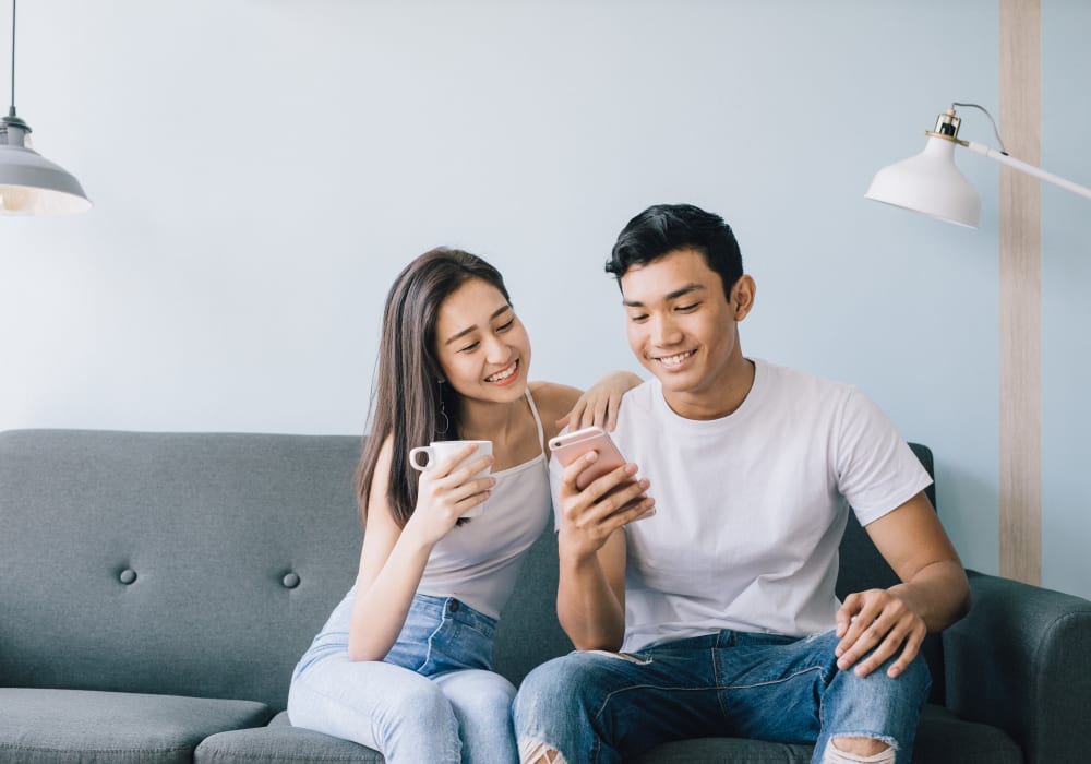 Resident couple browsing the web on a mobile device in their apartment home at Sofi Highlands in San Diego, California