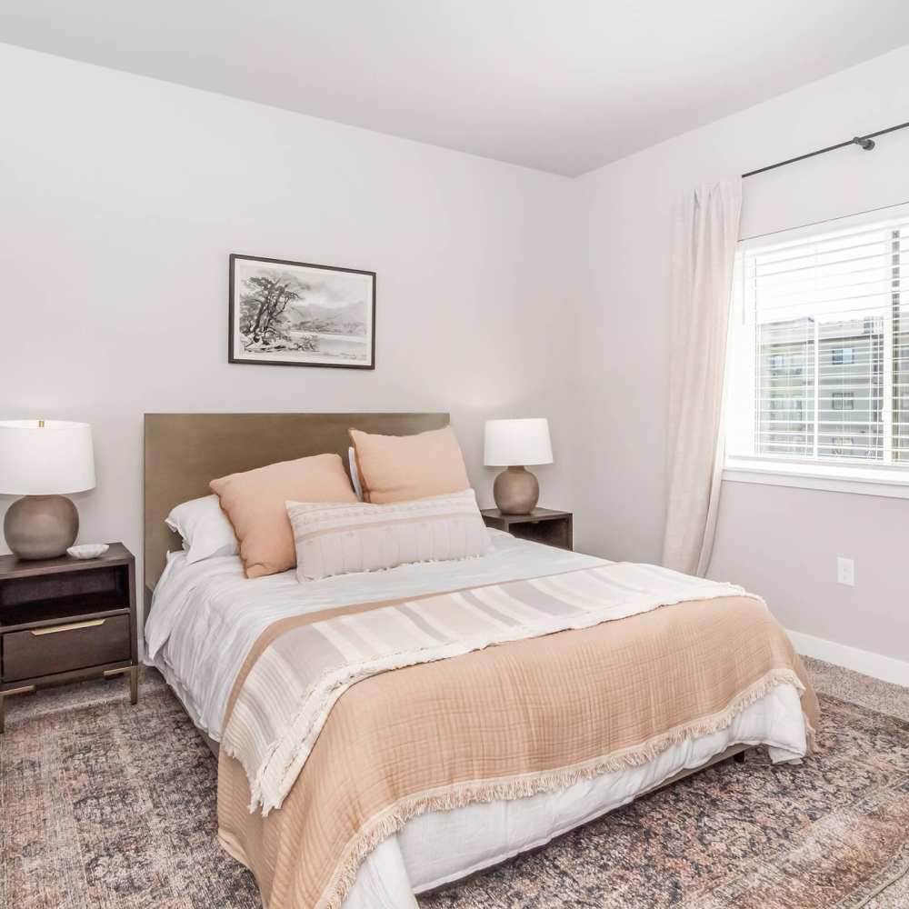Spacious bedroom with large bed, side table lamp and windowat InterUrban 2.0 in Billings, Montana