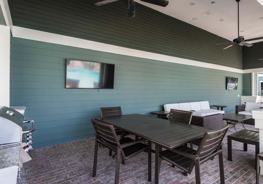 Clubhouse indoor lounge with TV, dining table and large windows at Southfork Lake in Manvel, Texas