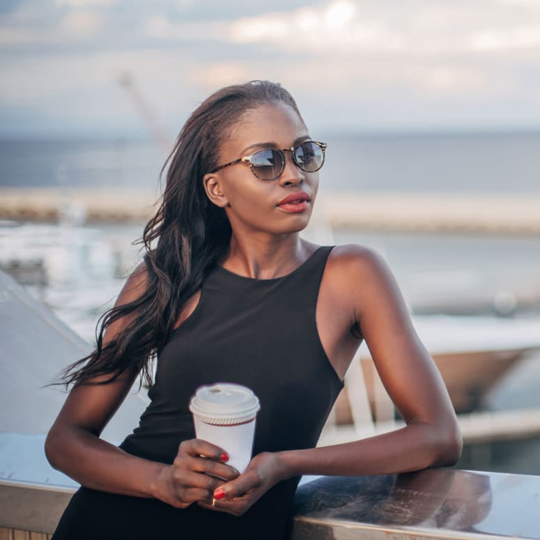 A woman having a coffee at the marina at Harborside Marina Bay Apartments in Marina del Rey, California