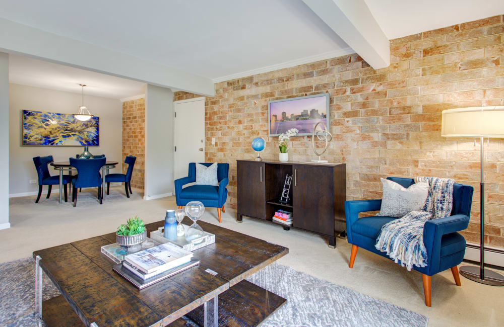 Spacious model living room and dining area with a brick accent wall at The Gates of Deer Grove Apartment Homes in Palatine, Illinois