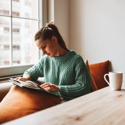 Resident reading by the window of her apartment at James River Pointe in Richmond, Virginia