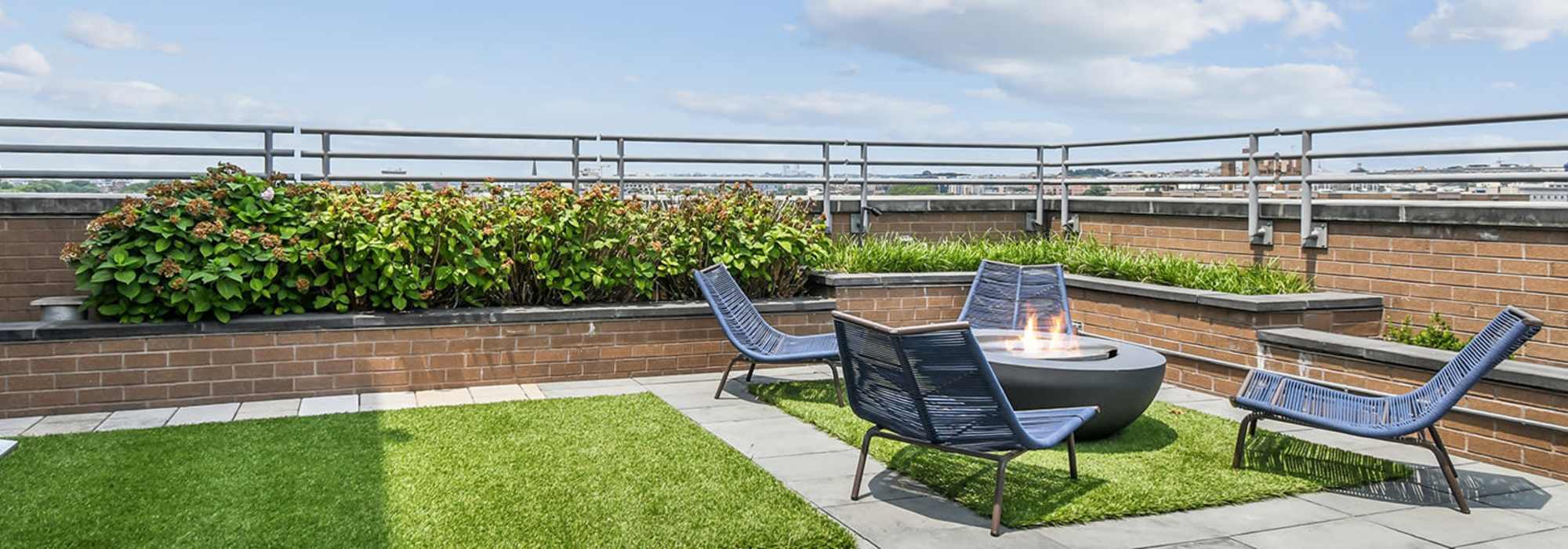 rooftop firepit area with seating and green turf at Apartments in DC