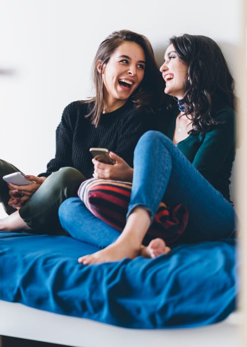 Friends sitting in bed and chatting at RISE at Riverfront Crossings in Iowa City, Iowa