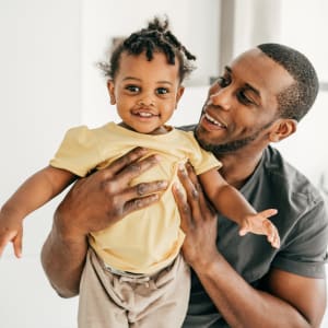 Resident holding up his cute toddler in their new home at The Majestic at Hewitt in Hewitt, Texas