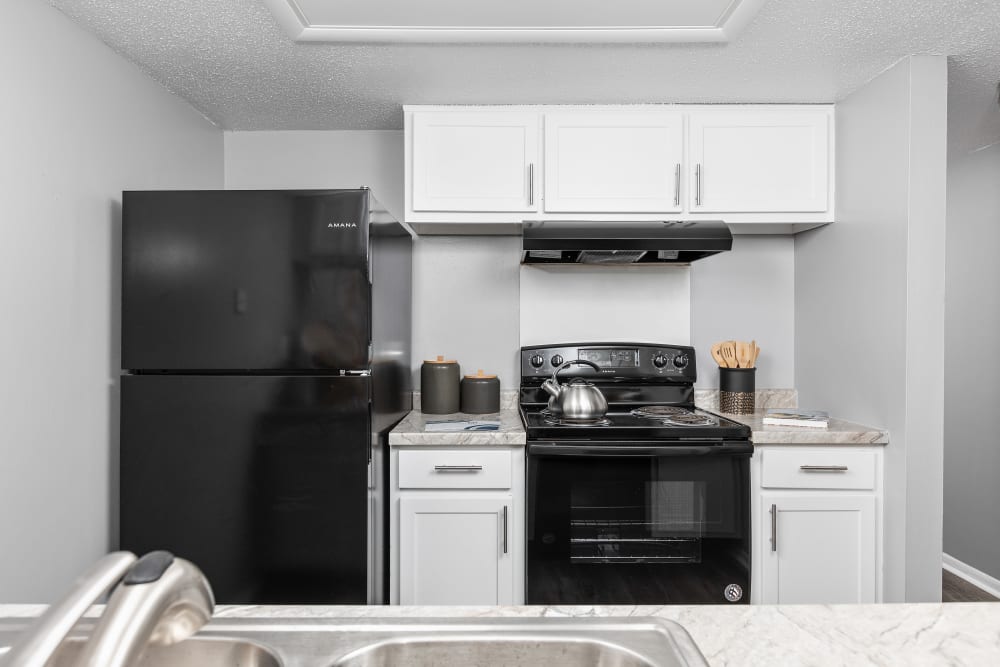 Kitchen with modern white cabinets and black appliances at Astoria Park Apartment Homes in Indianapolis, Indiana