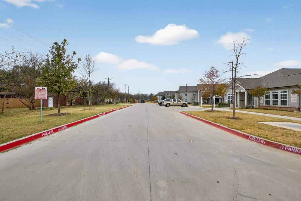 Charming street view with lush landscaping and modern homes at Lakewood Crossing in Granbury, Texas.