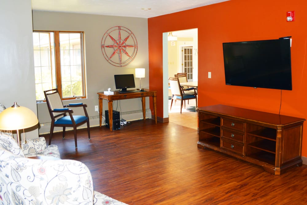 A television viewing area with warm red walls at Wyndemere Memory Care in Green Bay, Wisconsin.