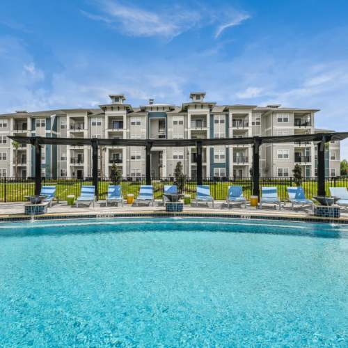Swimming pool with laid back chairs at Champions Vue Apartments in Davenport, Florida
