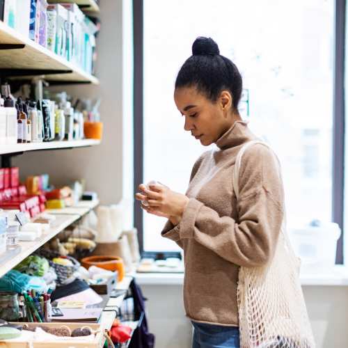 Woman browsing products on shelves in a cozy shop at Messina Luxury Apartments in New Smyrna Beach, Florida