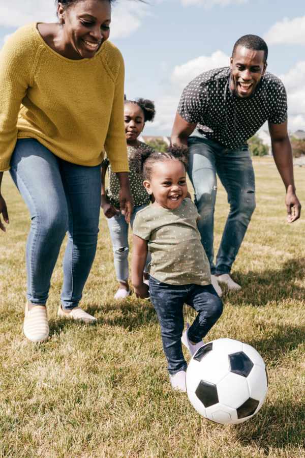 Resident family playing football in playground near The Abbey At Enclave in Houston, Texas