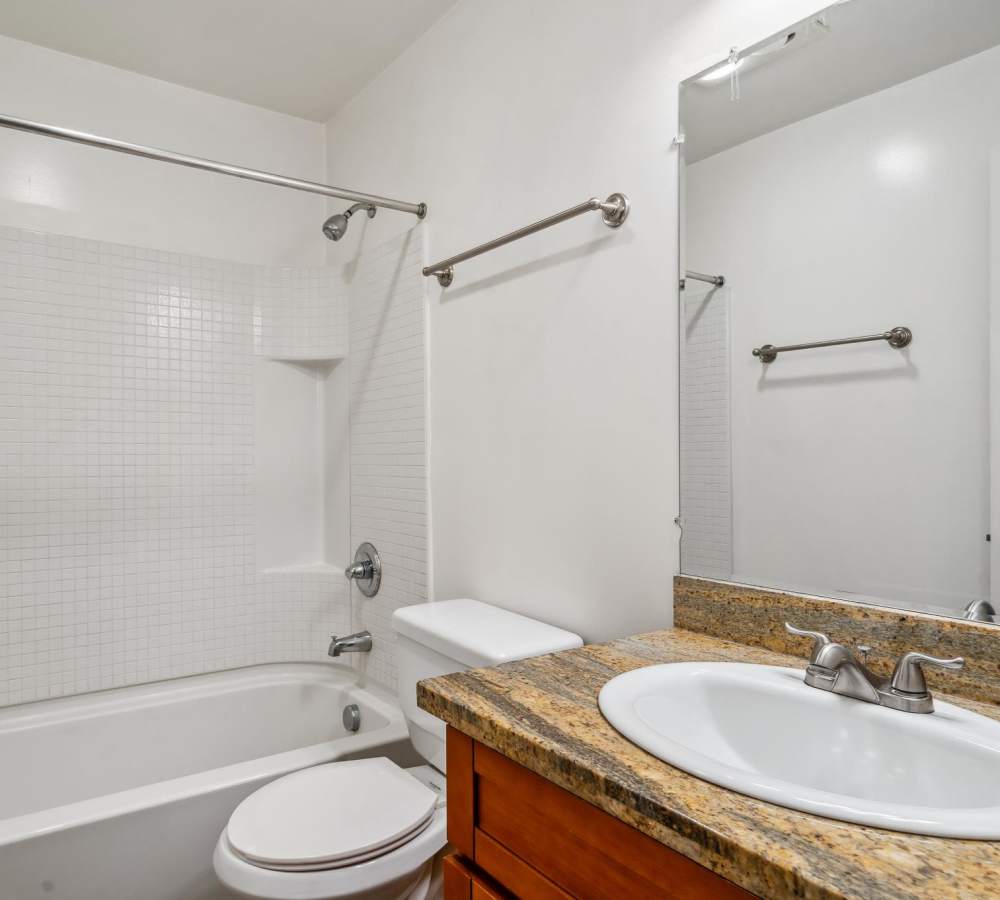 Bathroom at Regency Plaza Apartment Homes in Martinez, California features a shower tub combo and large vanity mirror