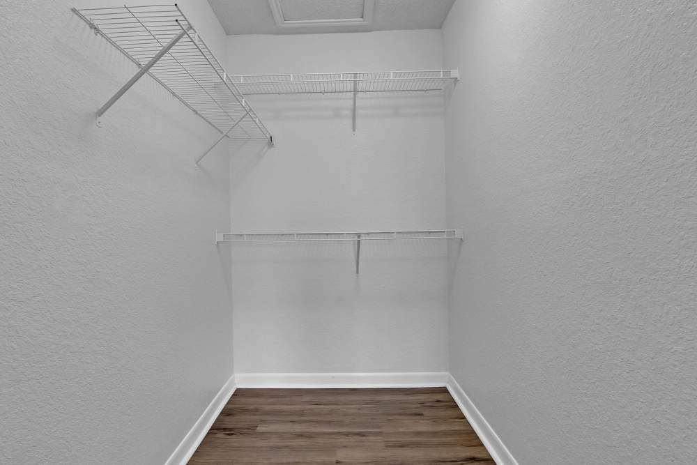 Walk-in closet with hanging racks and wood-styl flooring at Garden Courtyards in Tulsa, Oklahoma