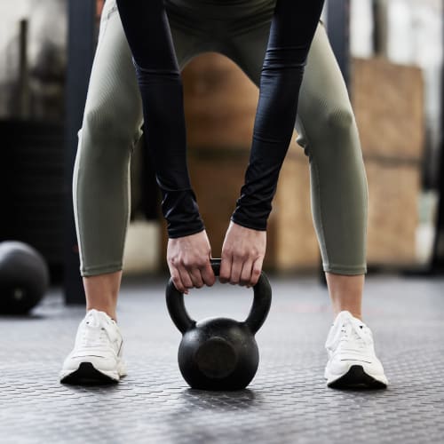 Resident lifting a kettlebell in the fitness center at The Brunswick in New Brunswick, New Jersey