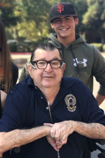 Resident with his grandson standing behind him outside at Quail Park on Cypress in Visalia, California