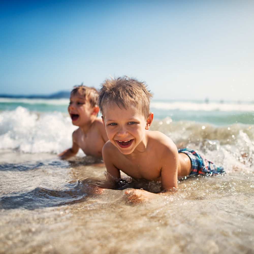 Two boys playing in the ocean waves at Dolphin Marina Apartments in Marina Del Rey, California